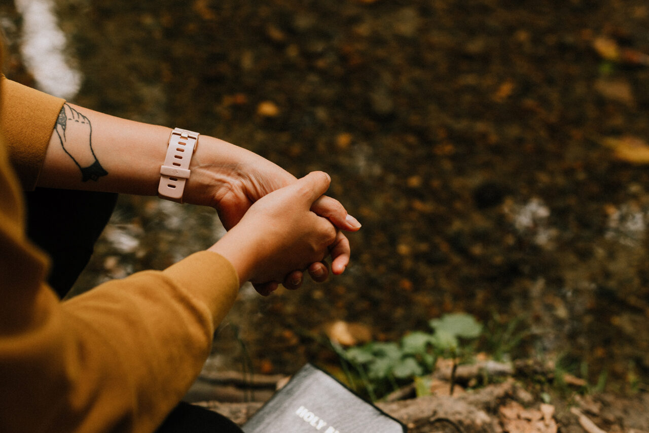 A close up photo of a woman's hands in prayer with her Bible as she sits in the outdoors. Prayer is a way through which Christians relate to God. Relatedness, in psychology, is one of the three needs in Self-Determination Theory.